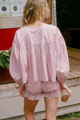 Person wearing a red and white striped outfit standing outdoors.