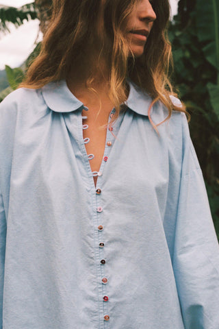 Light blue denim shirt worn by a person with a blurred natural background