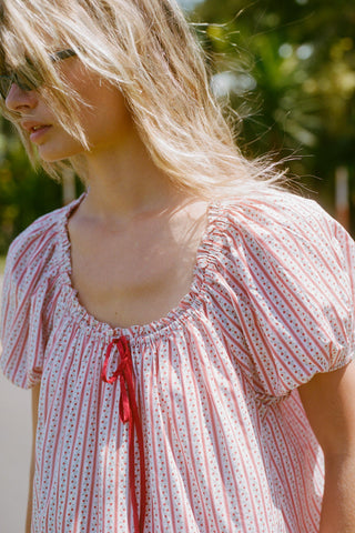 Woman wearing a red and white patterned dress with a close-up of the neckline with contrasting red tie.