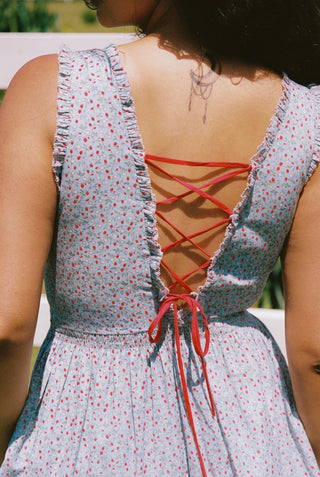 Back view of a blue and red floral dress with red corset ties worn by a person.