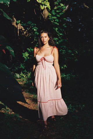 Woman in a red and white striped dress with red trim standing in a forest setting