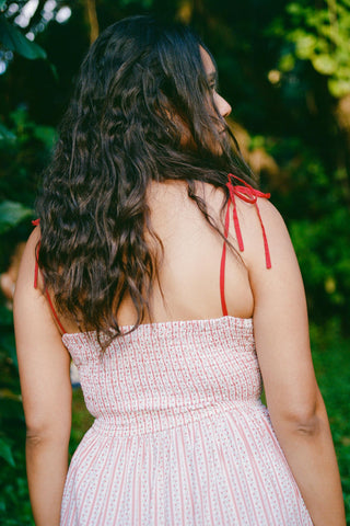 Woman in a red and white striped dress with red straps in a natural setting