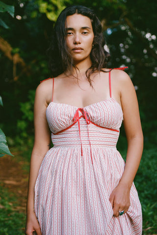 Woman wearing a red and white patterned dress with a forest background