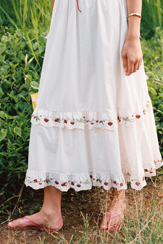 White dress with floral embroidery worn by a person in a natural setting