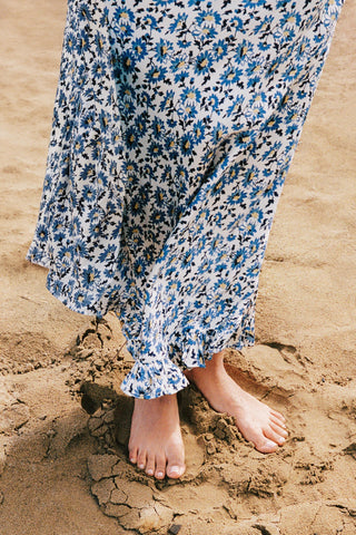 Person wearing a blue floral dress standing on sand