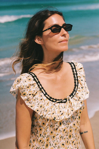 Woman wearing sunglasses and a patterned dress on a beach