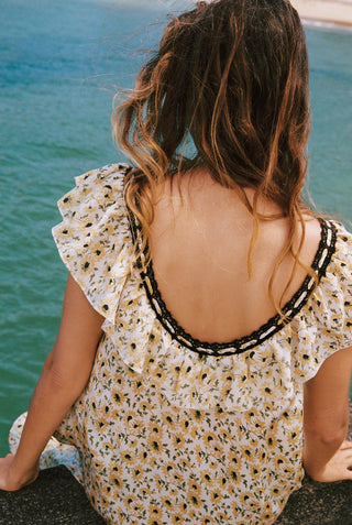 Woman in a floral dress with a beaded neckline sitting by a pool.