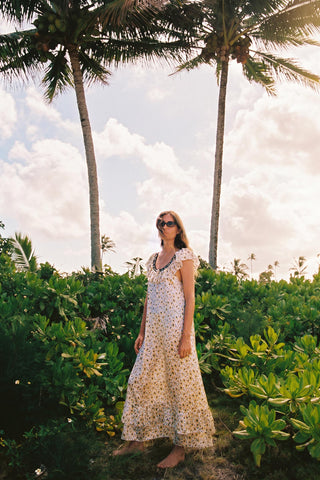 Woman in a floral dress standing among palm trees and greenery