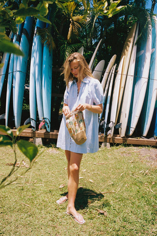 Woman in a chambray button down dress  standing in front of surfboards