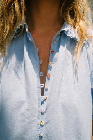 Close-up of a light blue button-up chambray dress with a blurred background