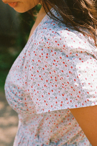 Close-up of a person wearing a blue and red floral dress with a blurred natural background