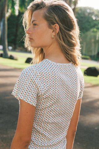 Woman wearing a floral patterned white shirt in an outdoor setting
