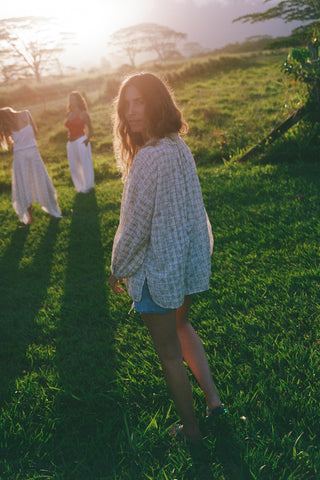 Woman wearing a patterned floral shirt standing in a grassy field with a blurred background