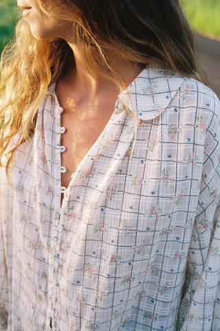 Close-up of a person wearing a checkered shirt with floral patterns.