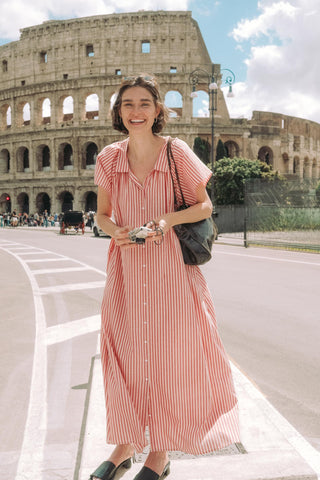 Woman in a red and white striped dress standing in front of the Colosseum.