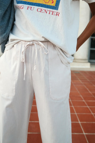Person wearing a light blue t-shirt with 'Kung Fu Center' text and white pinstripe pants on a red brick floor.