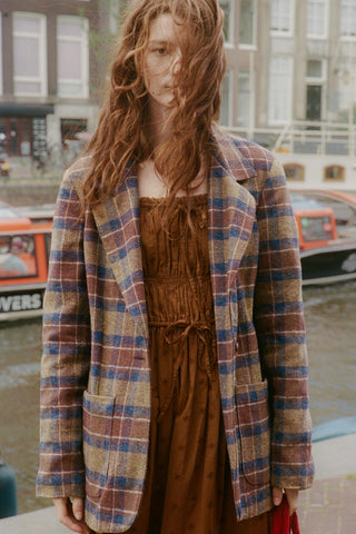 Women wearing a plaid blazer over the top of a brown dress