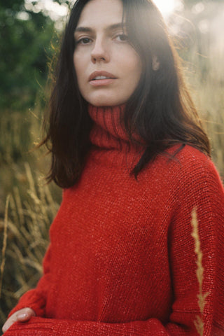 Woman wearing a red sweater with a turtleneck in a natural setting