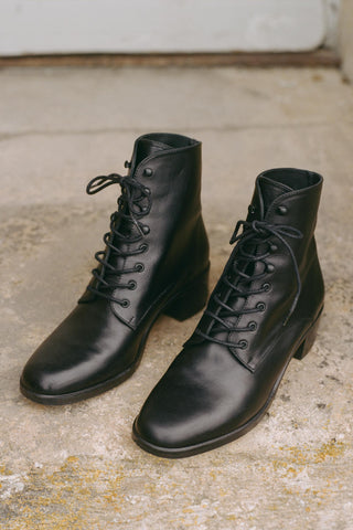 Pair of black leather boots on a concrete surface