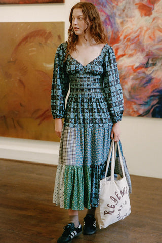 Woman in a patterned dress holding a tote bag in an art gallery setting