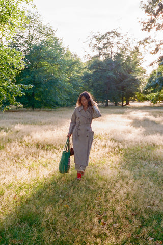 Woman walking through a sunlit field with trees in the background