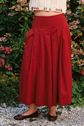 Baggy red pants with greenery in the background 