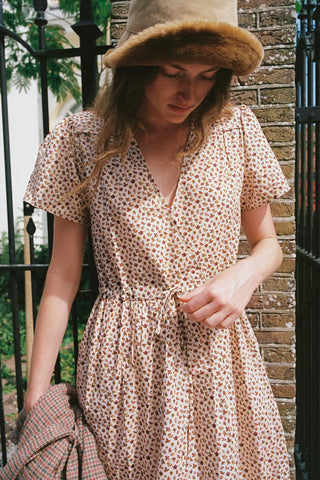 Women wearing a beige dress with a cozy hat holding a plaid item