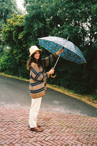 A woman wearing a cozy, oversized striped knit sweater holding an umbrella