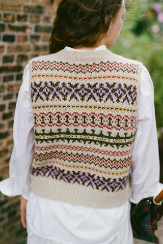 Back shot of a woman wearing a colorful vest over a white shirt 