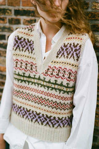 Woman wearing a colorful vest over a white shirt