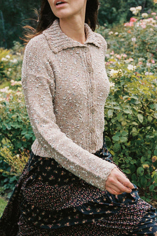 Woman wearing a beige textured knitted sweater in a garden setting
