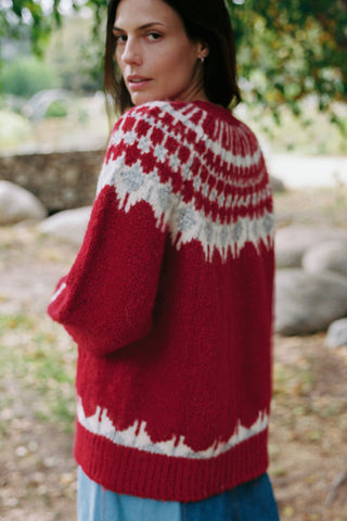 Woman wearing a red and white patterned sweater outdoors.