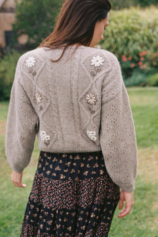 Woman wearing a knitted cardigan with floral patterns in an outdoor setting