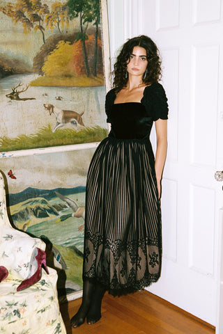 Woman in a black dress standing in front of a painting