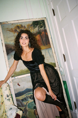 Woman in a black dress posing in front of a painting