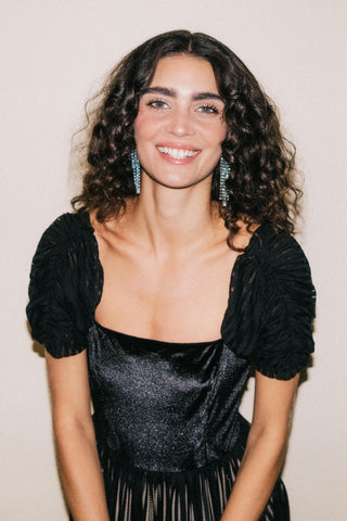 Woman wearing a black dress with puffed sleeves against a plain background
