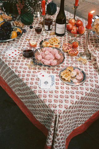 A floral block printed tablecloth on a decorated table with wine, candles, fruit and flowers.