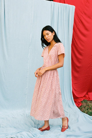 Woman in a red dress standing against a light blue and red fabric backdrop