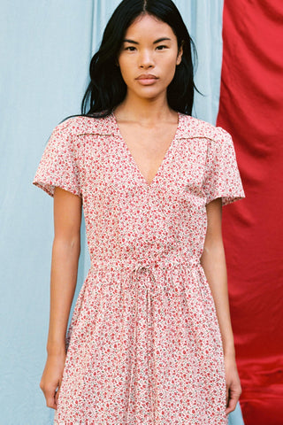 Zoomed in shot of a woman wearing a red floral dress against a red and blue background