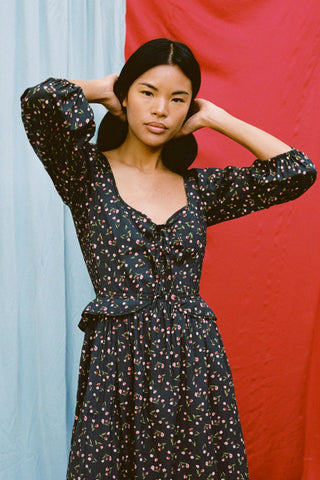 Woman wearing a black floral dress against a red and blue background