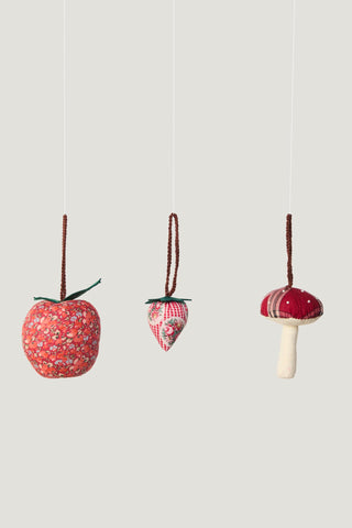 Three fabric ornaments shaped like an apple, strawberry, and mushroom on a light gray background.