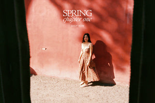Women in a red floral dress leaning against a bright red wall