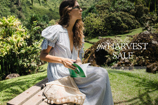 A woman wearing a short-sleeve floral dress stands against a bright yellow wall with a green stripe at the bottom. Large sale text overlays the center of the image, including 'the HARVEST SALE' and a 'SHOP NOW' button.