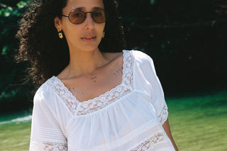 Woman wearing a white lace top with a blurred green background