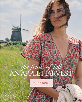 woman in a floral dress in a field with the words the fruits of fall an apple harvest shop now