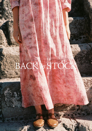 Person wearing a pink dress standing on stone steps with 'Back in Stock' text overlay.