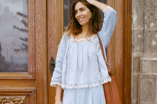 Woman in a light blue dress standing in front of a wooden door.