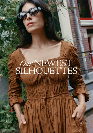 A woman wearing a brown long-sleeve dress with ruffled sleeves and a smocked bodice, styled with black sunglasses. The image features a text overlay reading 'Our NEWEST SILHOUETTES' across the center.