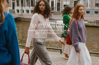 Three women walking along a canal-side path in an outdoor urban setting, wearing soft knit sweaters and dresses. Large overlaid text reads 'EARLY AUTUMN' with a quote beneath and 'SHOW NOW' below, suggesting a fashion promotional banner.