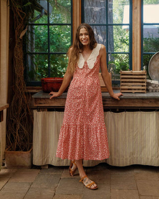 Woman in a red floral dress standing in a rustic kitchen.